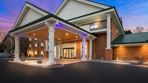 A hotel with a covered entrance, brick facade, and a balcony.