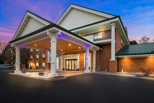 A hotel with a covered entrance, brick facade, and a balcony.