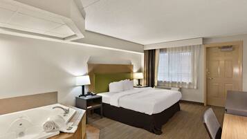 Une chambre d’hôtel avec un grand lit, une salle de bain séparée avec une baignoire, un bureau et une chaise.