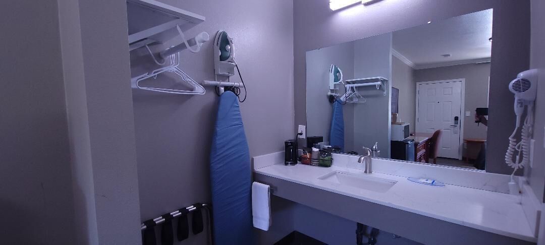 Un baño con un lavabo blanco, un espejo, un secador de pelo y un toallero.