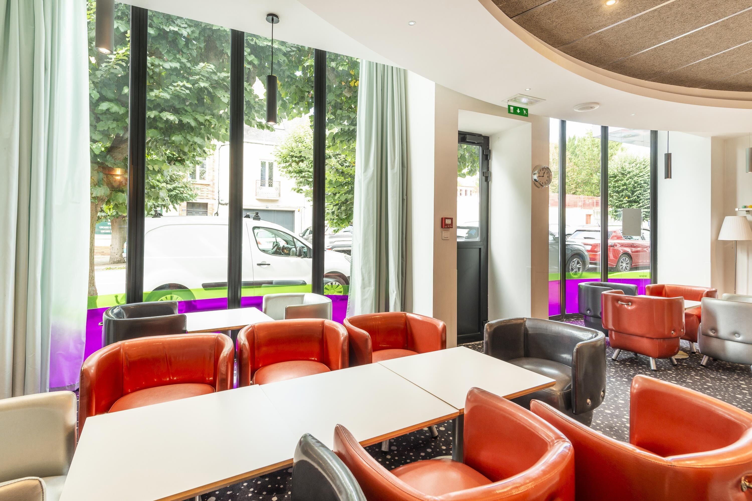 A modern hotel lobby with large windows, leather seating, and a clean, bright interior.