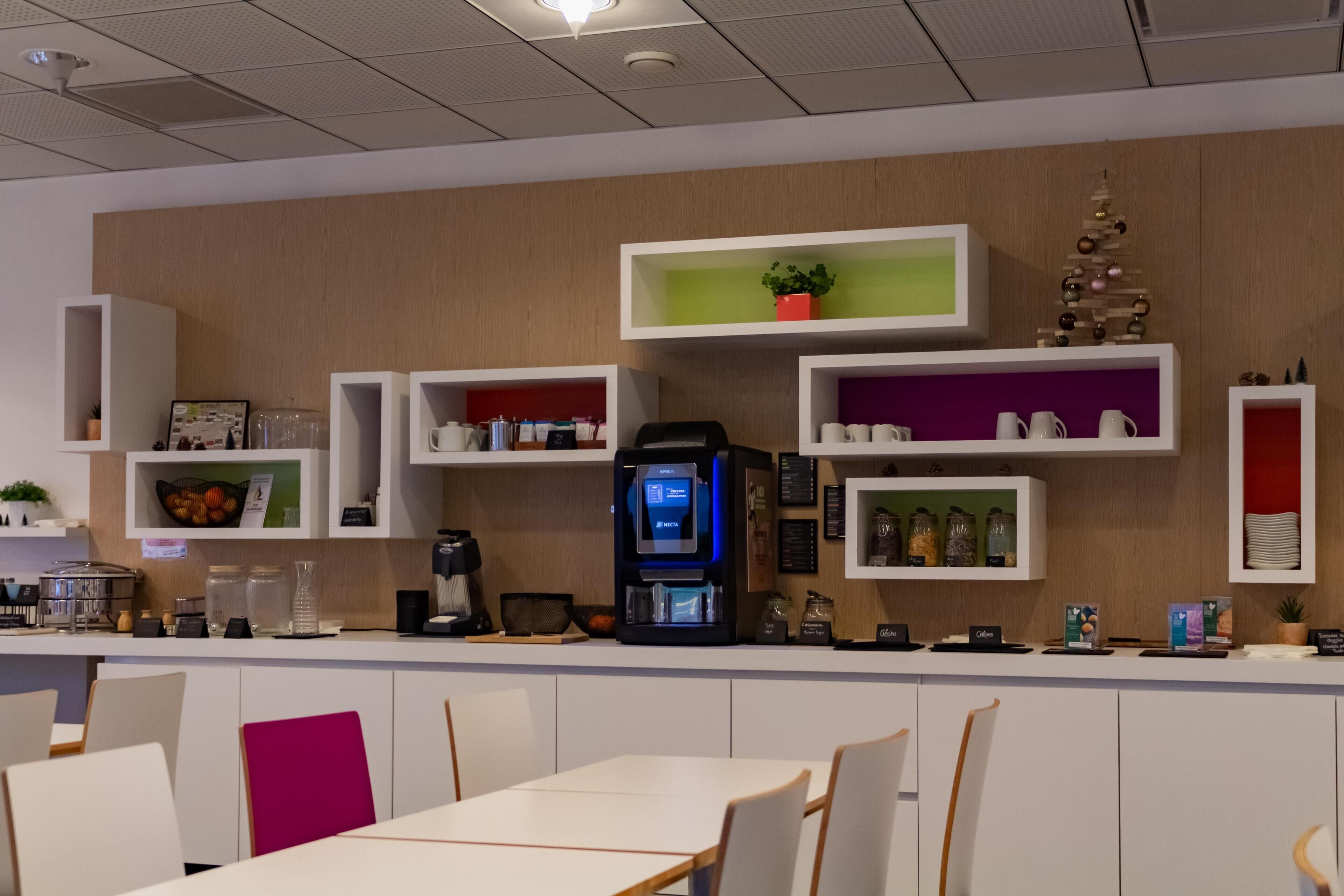 Un café moderne avec des meubles blancs, une machine à café et des étagères remplies de divers objets.