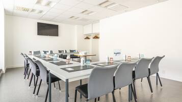 A conference room with a long table, multiple chairs, a flat-screen TV, and a sign reading "myWO".