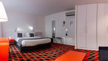 Una habitación de hotel con cama, escritorio, silla, armario y suelo estampado.