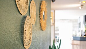 Ein Zimmer mit grüner Wand, einem Holztisch mit Pflanze und drei gewebten Wandbehängen.