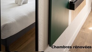 Ein modernes Hotelzimmer mit einem großen Bett, einem wandmontierten Flachbildfernseher und einer Wand in Grünton.