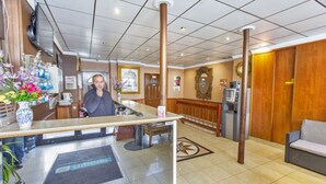 A hotel reception area with a reception desk, a sofa, a coffee machine, and a large mirror on the wall. - Hipotel Paris Printania Maraîchers (Paris)