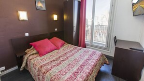 A hotel room with a large bed, a wardrobe, a desk, and a window with a view of the city. - Hipotel Paris Printania Maraîchers (Paris)
