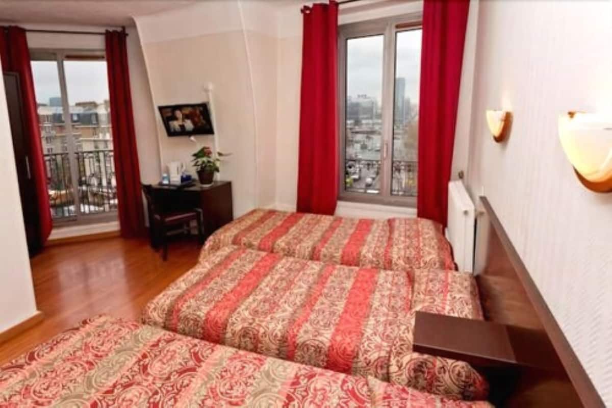 Un dormitorio con una cama grande, un escritorio y vistas a la ciudad a través de una ventana.