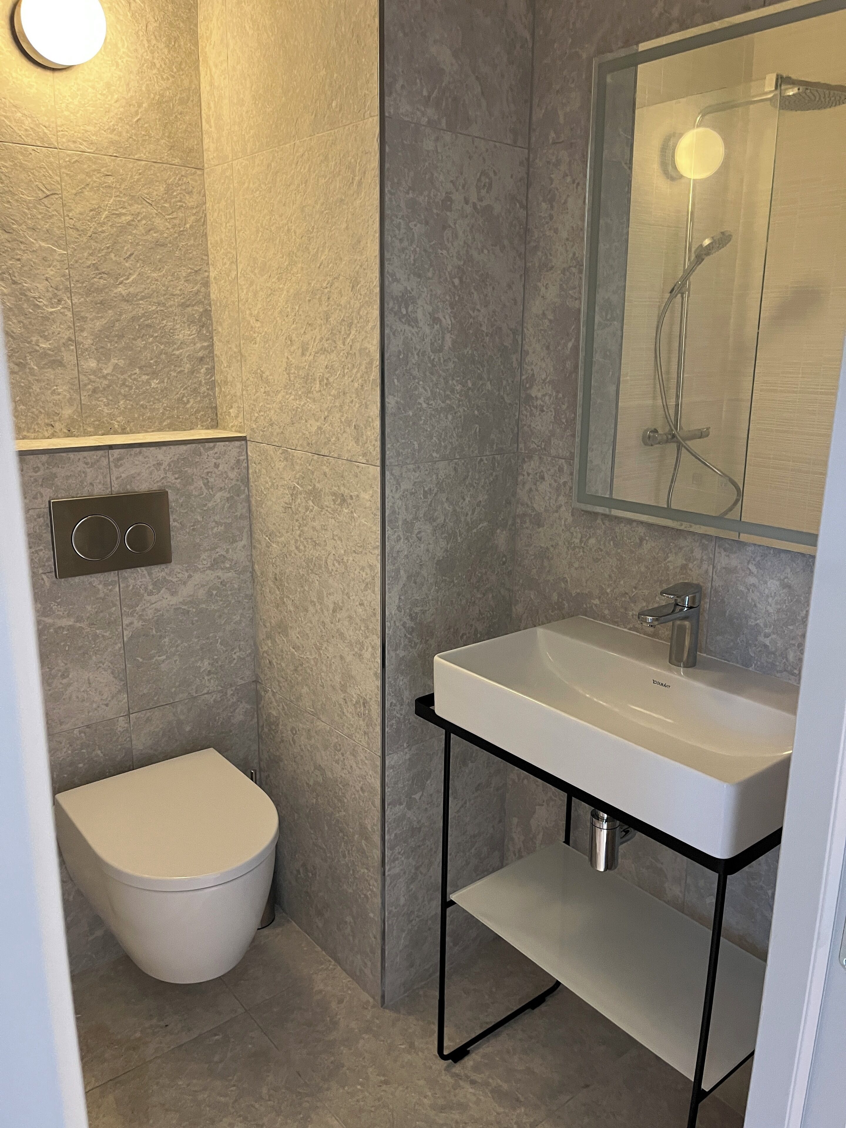 A modern bathroom with a toilet, a sink, and a shower.