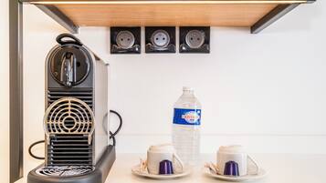 A coffee machine with a water bottle and two cups on a white countertop.