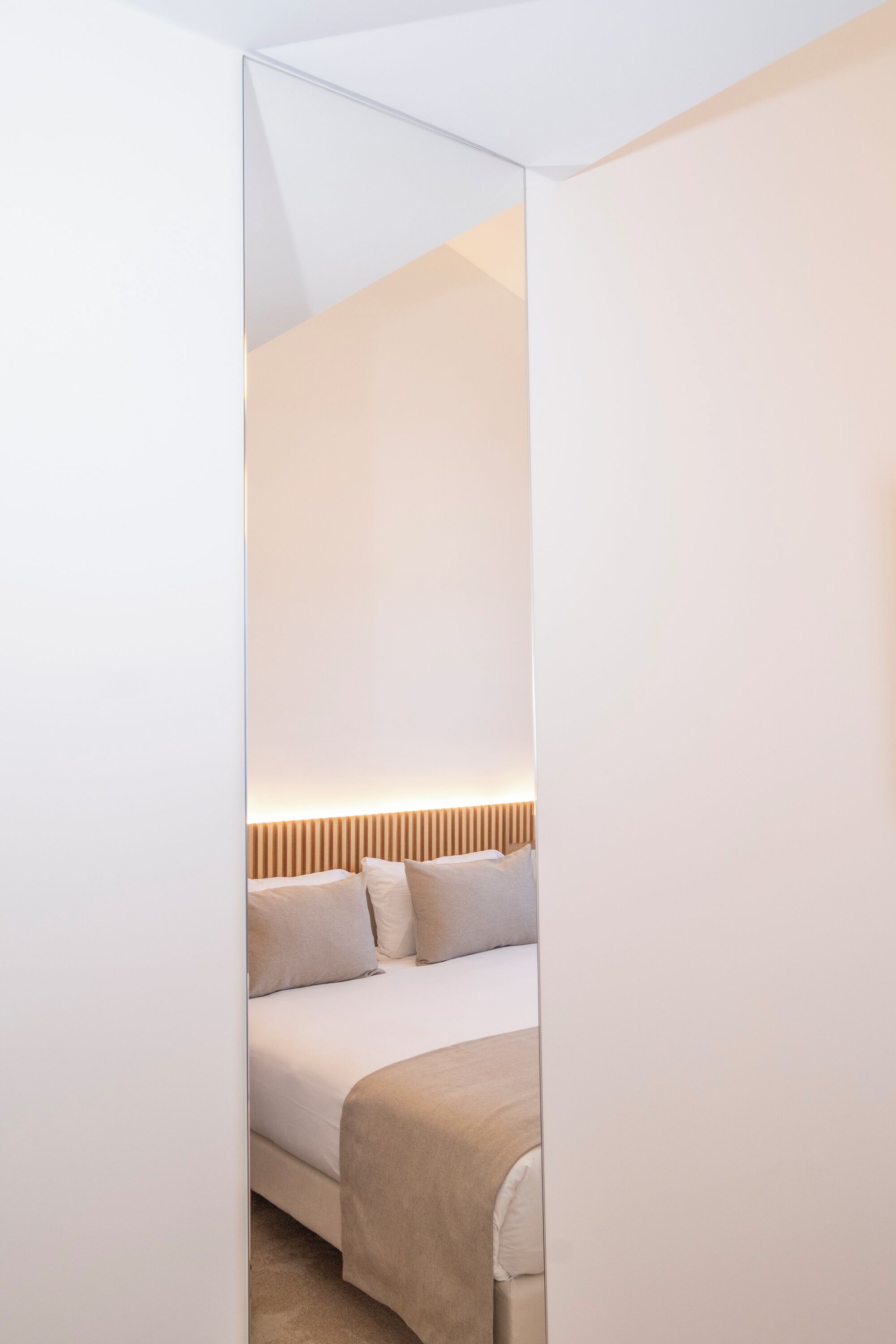 A modern bedroom with a bed, a bedside table, and a headboard with vertical lines.
