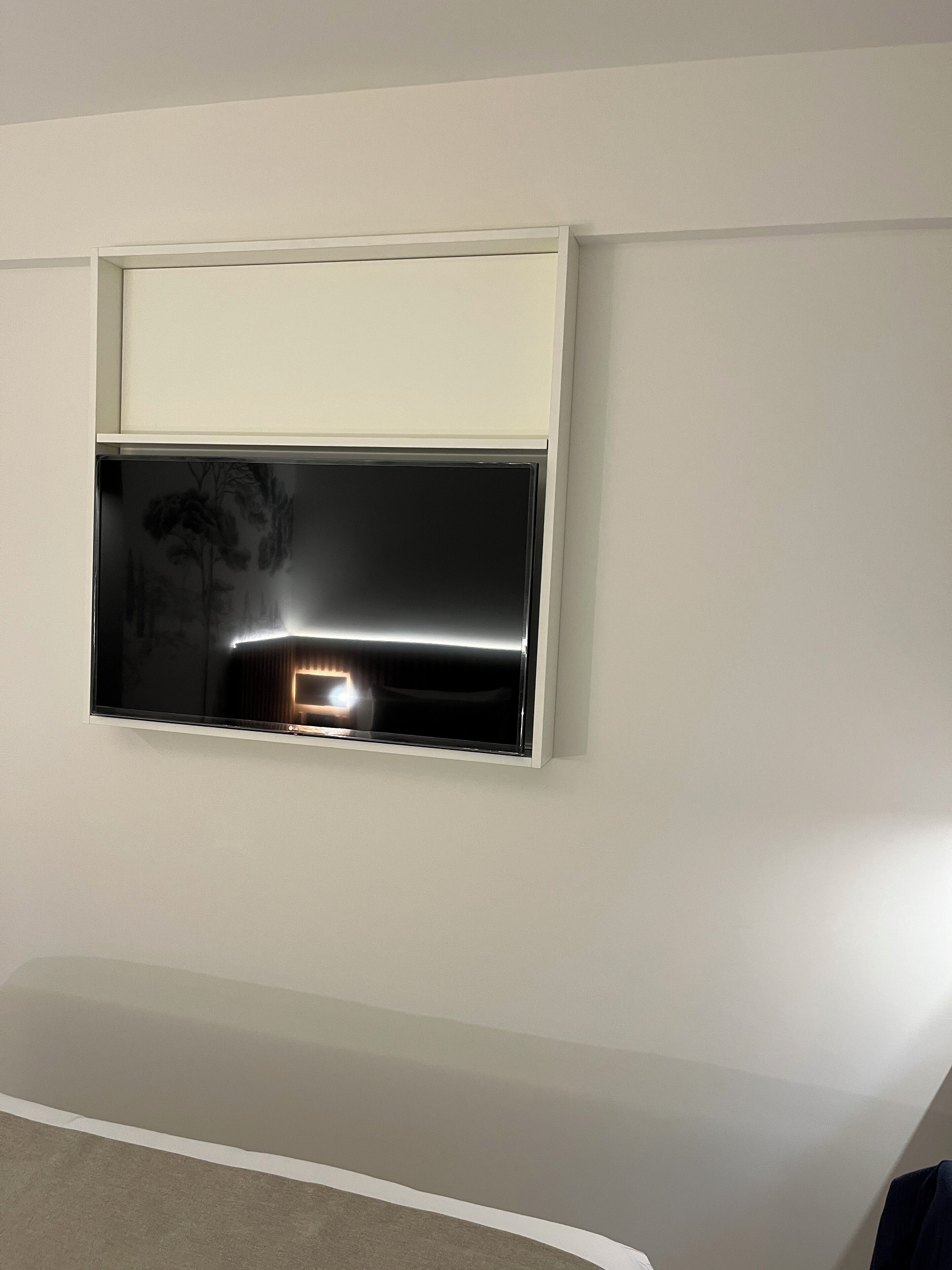 A white wall with a recessed ceiling light fixture and a white cabinet above it.