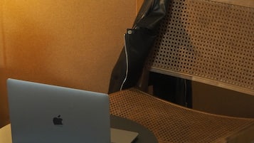 Un ordenador portátil sobre una pequeña mesa redonda, con una silla de mimbre al lado.