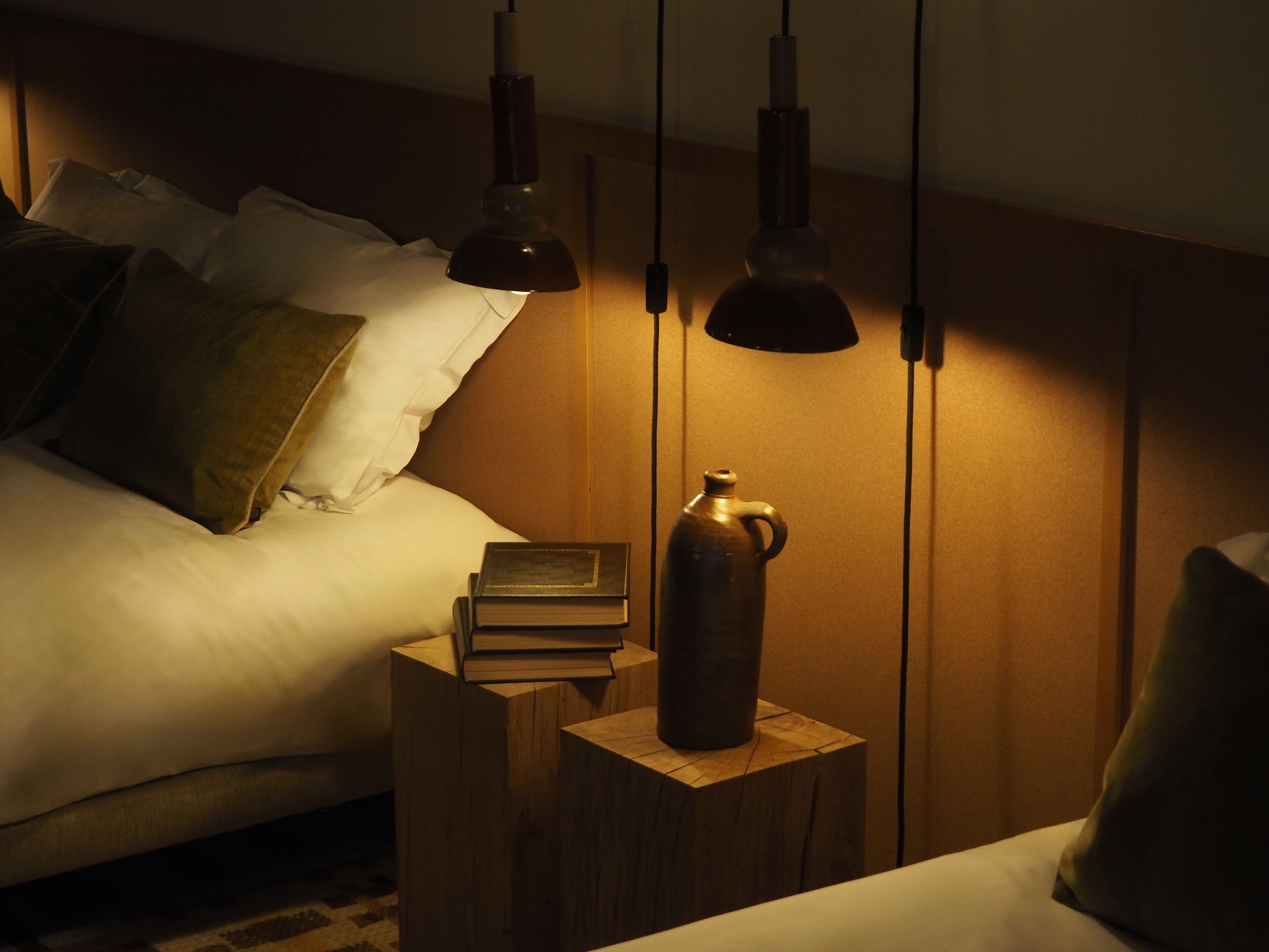 Une chambre à coucher avec un lit, des tables de chevet et des lampes suspendues.