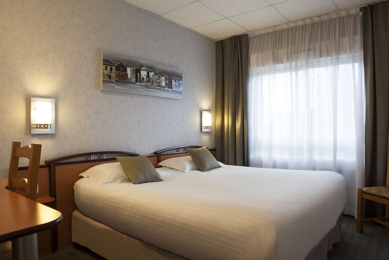 Een hotelkamer met een groot bed, twee nachtkastjes, een bureau en een stoel.