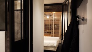 A hotel room with a bed, a wooden slatted window blind, and a hanging light fixture. - The Originals Boutique, Hotel La Chaussairie, Rennes (Chartres-de-Bretagne)