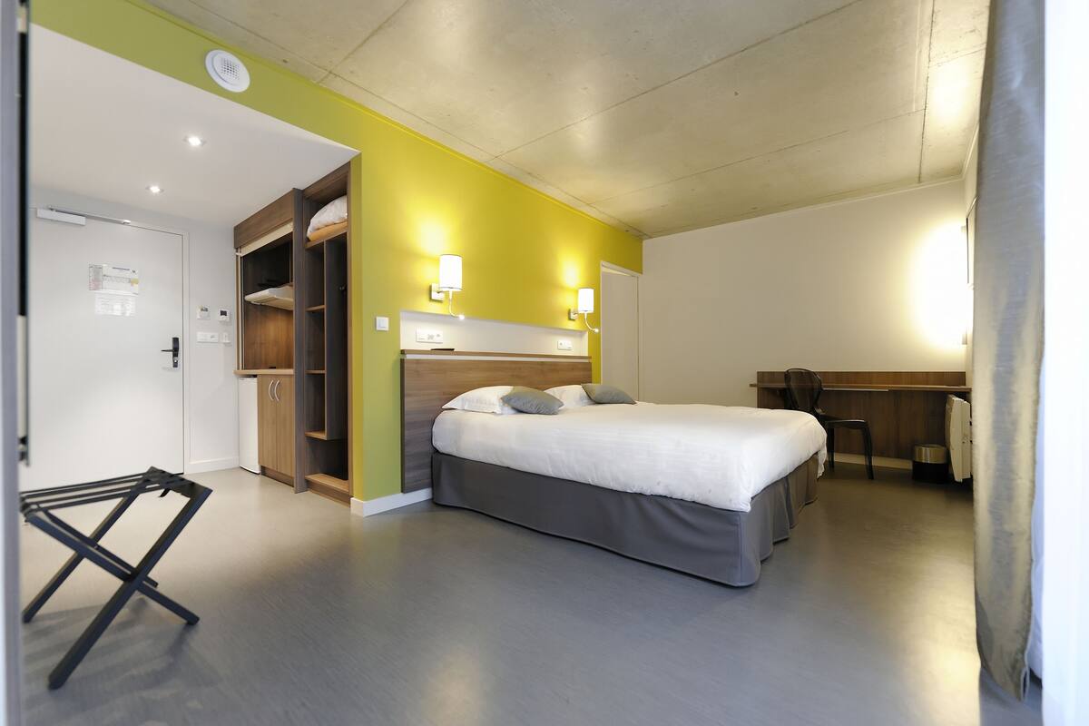 A bedroom with a bed, a desk, and a wardrobe.