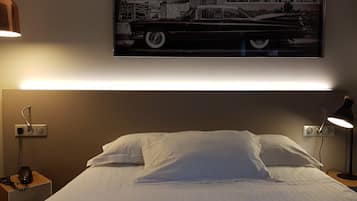 A hotel room with a bed, bedside lamps, a telephone, and a framed picture on the wall.