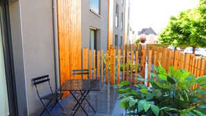 A patio with a metal table and two chairs, a wooden fence, and a potted plant. - The Originals Boutique, Hotel La Chaussairie, Rennes (Chartres-de-Bretagne)