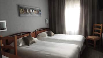 Une chambre d’hôtel avec deux lits, une chaise en bois, un téléviseur et un tableau au mur.