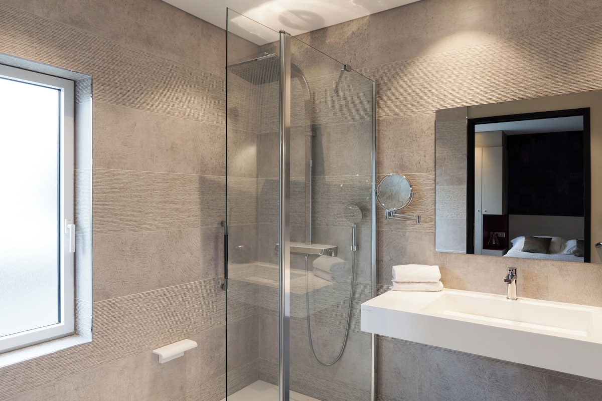 A modern bathroom with a glass-enclosed shower, a white sink, and a large mirror.
