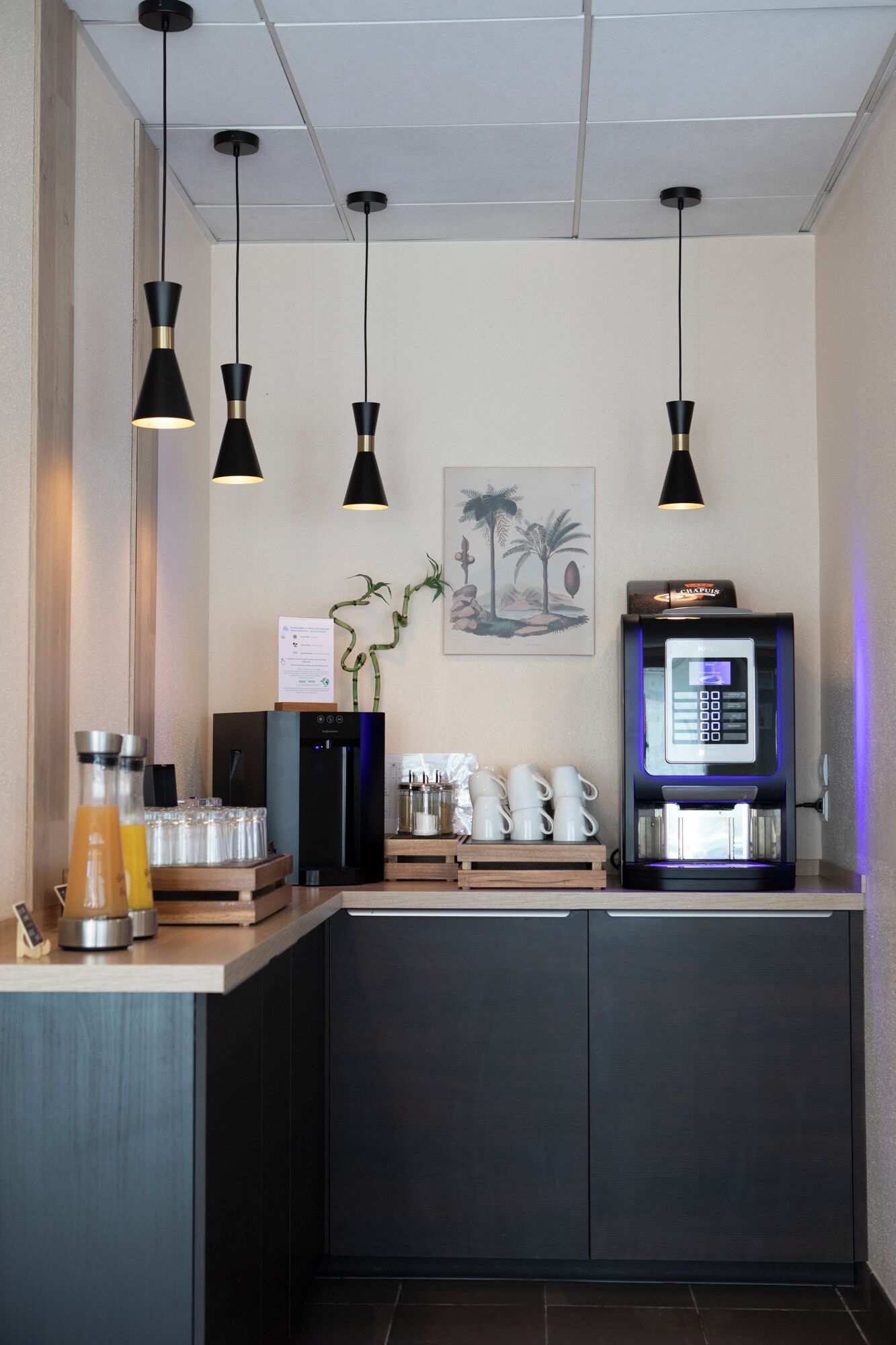 A modern coffee station with a digital coffee machine, a menu board, and a plant.
