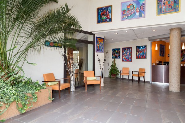Eine Lobby mit Sitzgelegenheiten, einem Empfangsbereich und Kunstwerken an den Wänden.
