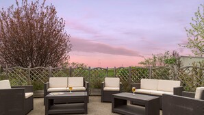 An outdoor seating area with wicker furniture and a view of a tree and sky.