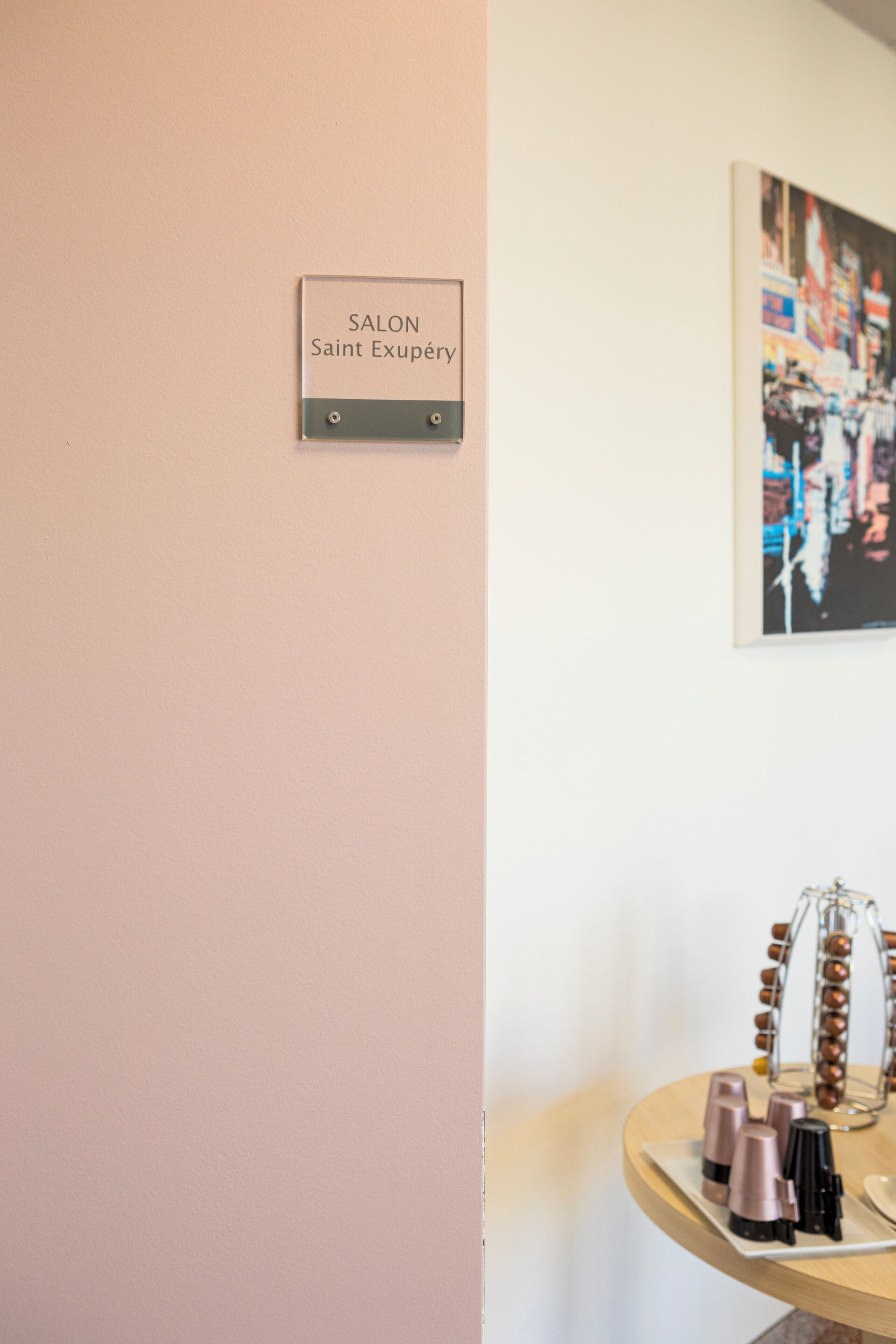 A salon sign, a framed artwork, and a display of cosmetics on a table.