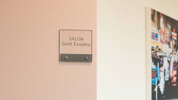 A salon sign, a framed artwork, and a display of cosmetics on a table.