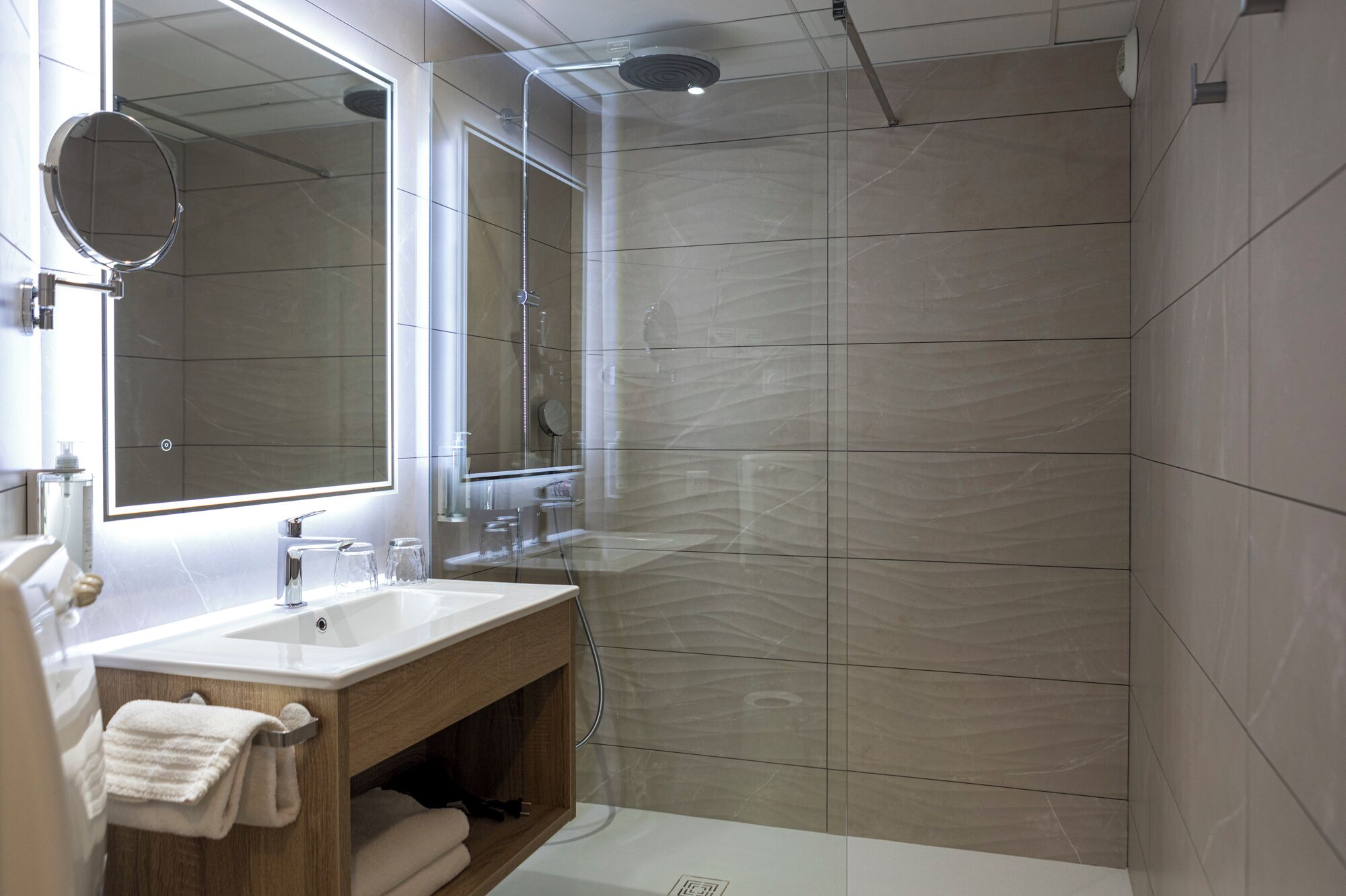 A modern bathroom with a vanity, a shower, and a large mirror.