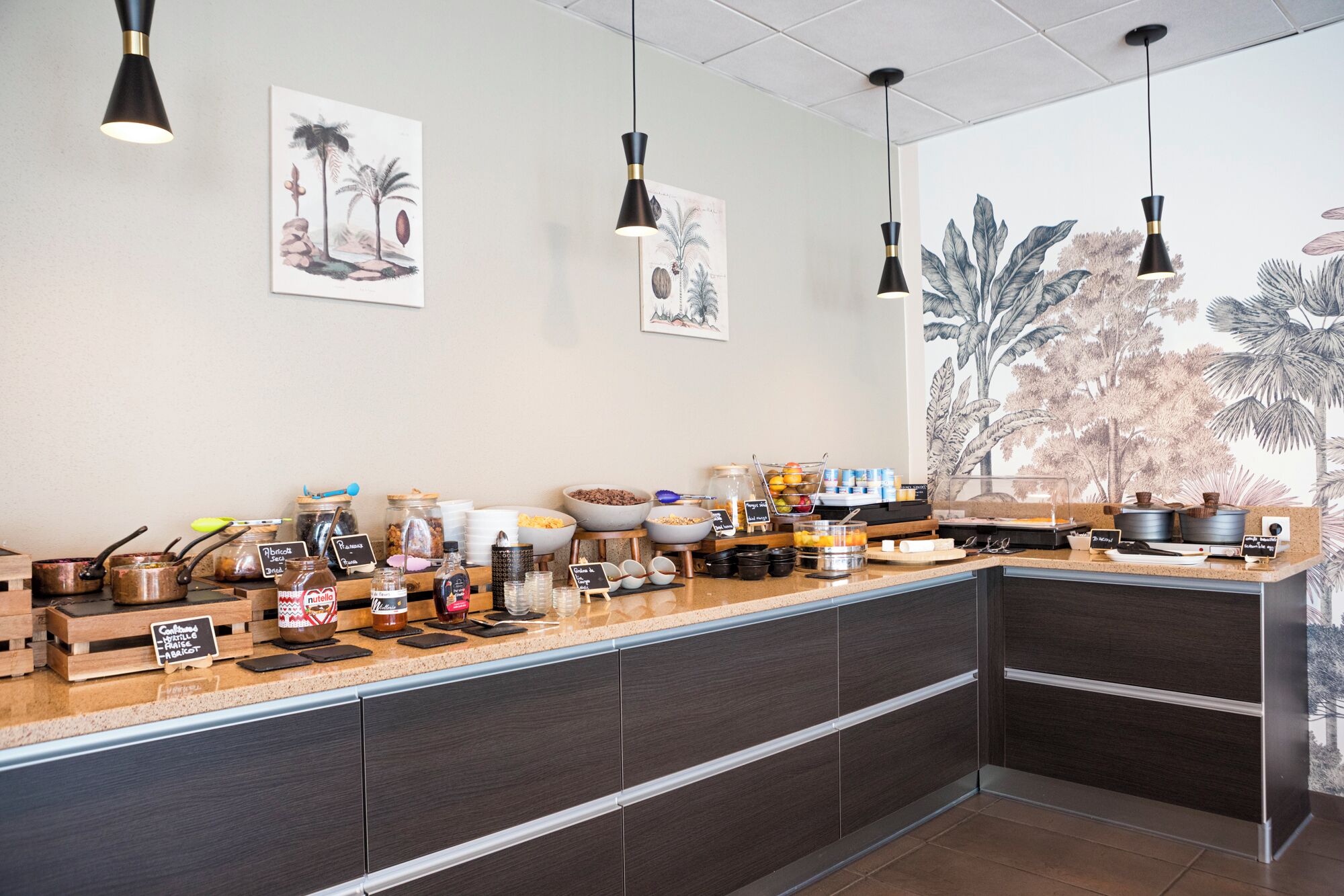 Une cuisine moderne avec un long comptoir, divers produits alimentaires et des œuvres d’art décoratives accrochées au mur.