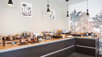 Une cuisine moderne avec un long comptoir, divers produits alimentaires et des œuvres d’art décoratives accrochées au mur.