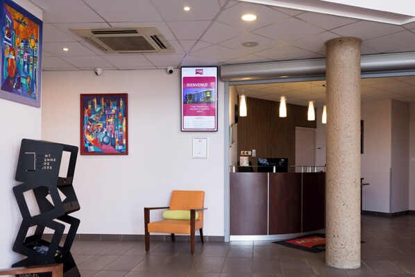 A reception area with a modern design, including a reception desk, a chair, and a large pillar.
