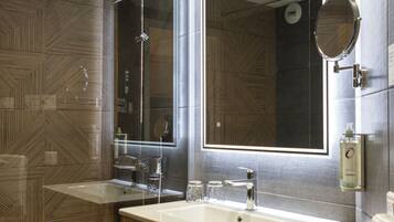 Une salle de bain moderne avec un grand miroir, deux lavabos, une douche et un meuble-lavabo en bois.