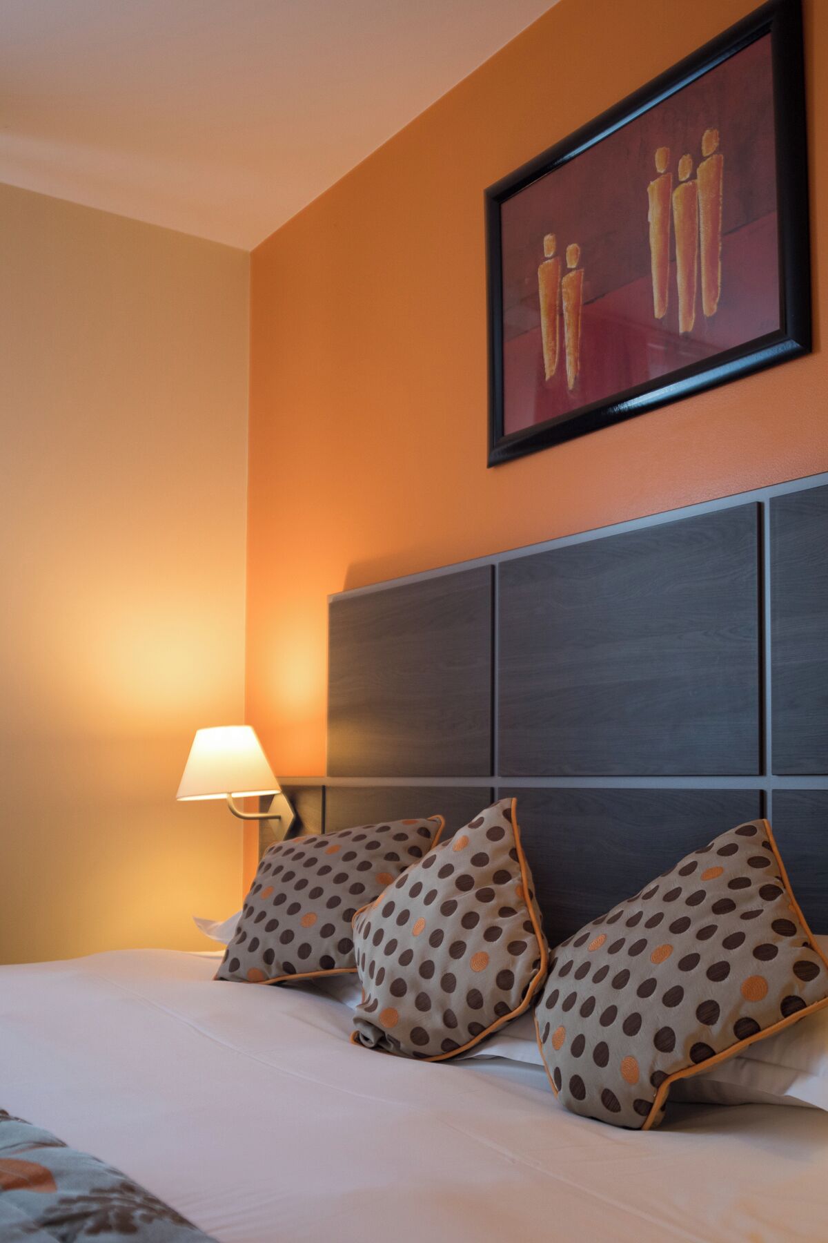 Una habitación de hotel con una cama, un cabecero y un cuadro colgado en la pared.