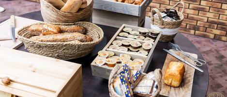 Variedad de panes y pasteles expuestos sobre una mesa con cestas y cajas de madera.