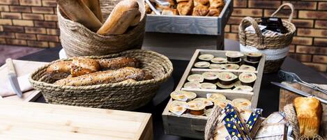 A variety of breads and pastries displayed in baskets and wooden boxes, suggesting a bakery or breakfast setting.