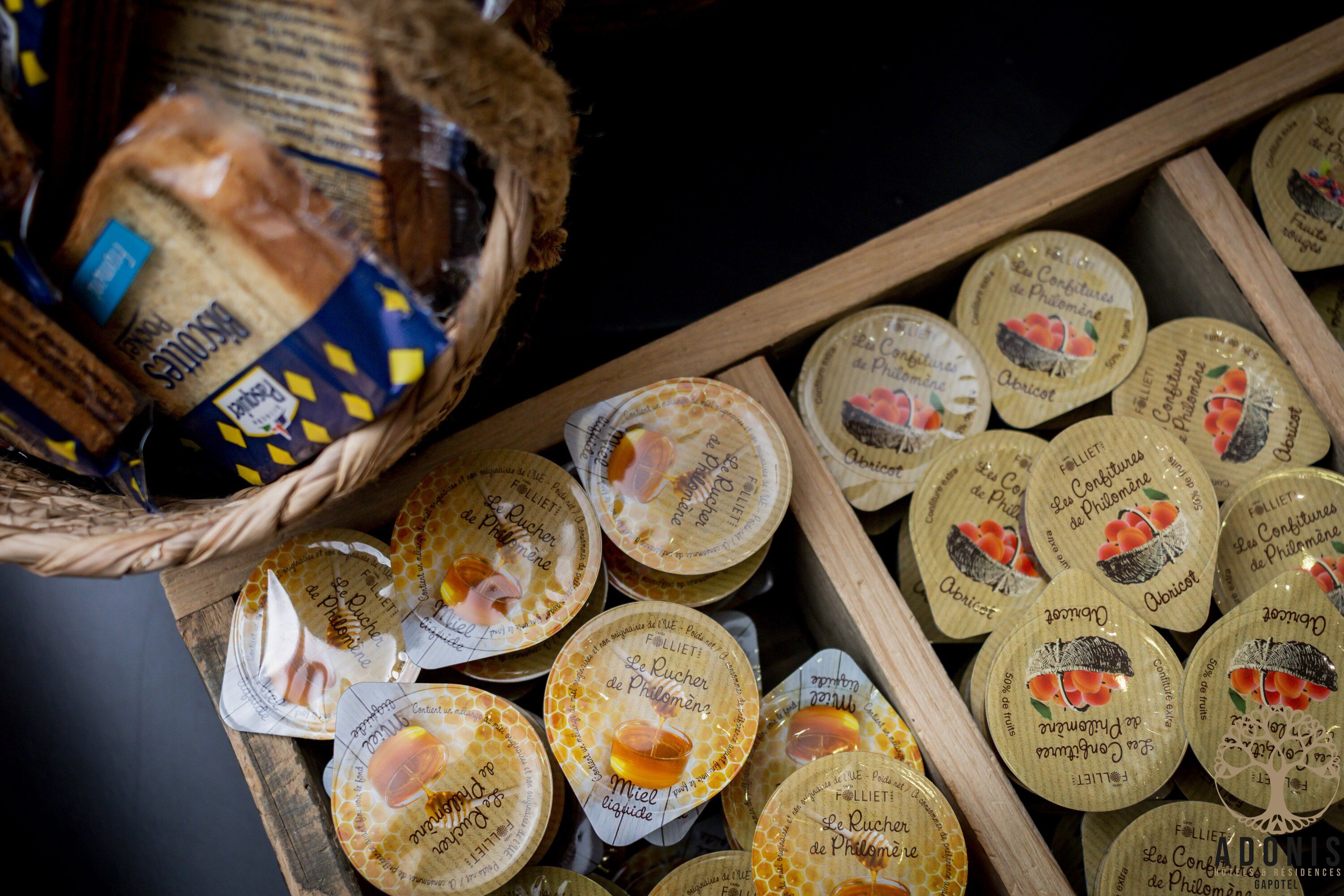 A wooden tray filled with honey jars and a basket of bread.