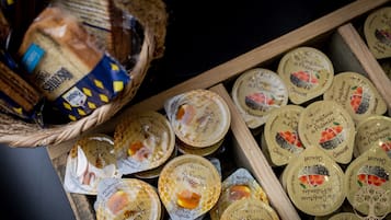 A wooden tray filled with honey jars and a basket of bread.