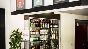A bar area with a variety of liquor bottles and glasses, a sign prohibiting smoking, and three framed posters above the bar. - Adonis Gapotel (Gap)