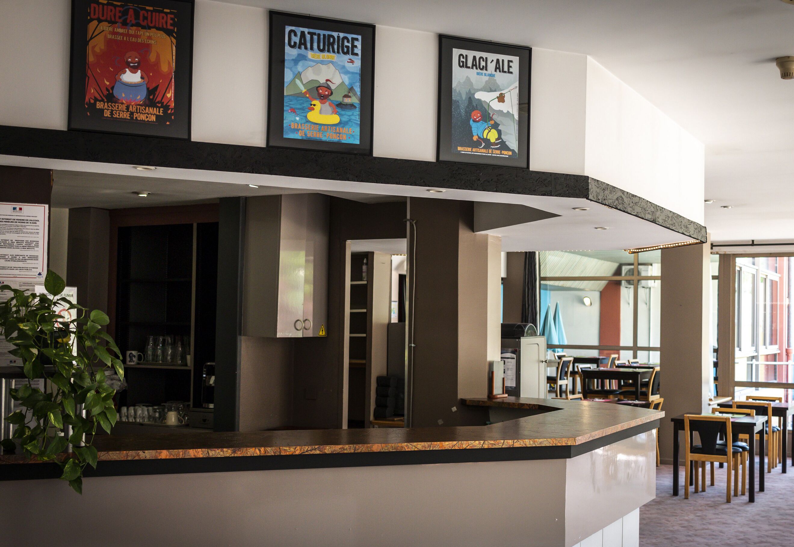A reception area with a counter, posters, and a seating area with tables and chairs.