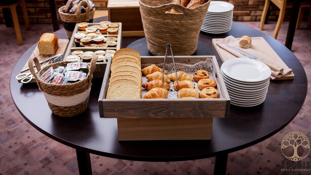 A buffet table with various food items, including bread, pastries, and a basket of magazines. - Adonis Gapotel (Gap)