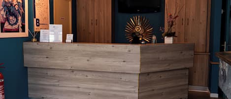 A reception desk with a wooden finish, a mounted television, and pendant lighting.