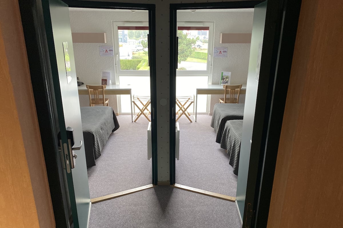 A room with two beds, a desk, and a chair.