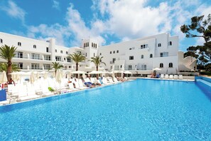 Una piscina techada, una piscina al aire libre, sombrillas