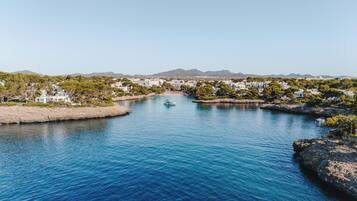 Un pueblo costero con un puerto deportivo, costa rocosa y edificios residenciales.