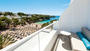 A balcony with a white railing, a small round table, and a blue cushion. - Grupotel Rocador (Santanyi)