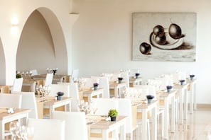 Ein Restaurant mit weißen Tischen und Stühlen, die in Reihen angeordnet sind.